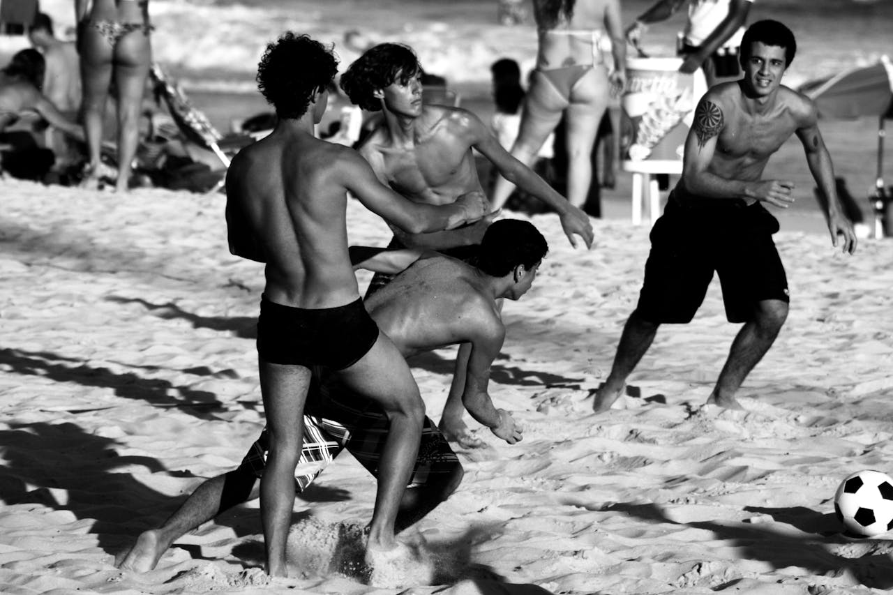 Black and white photo of young men enjoying a beach soccer game in Rio de Janeiro, Brazil.